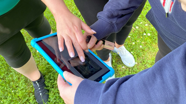 Tablet jako mapa pokladů – moderní piráti v akci Detail rukou účastníků používajících tablet při hře Treasure Hunt