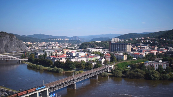 Město mezi skalami a řekou – ideální hřiště pro dobrodružství Letecký pohled na město rozkládající se podél řeky, s viaduktem a skálou