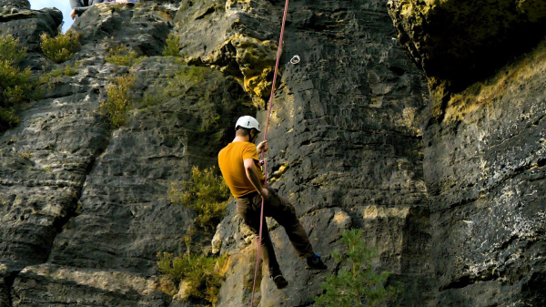 Účastník překonává skalní překážku při teambuildingu Ztraceni